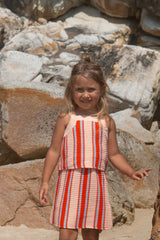 Young girl in a striped top and skirt standing among rocks