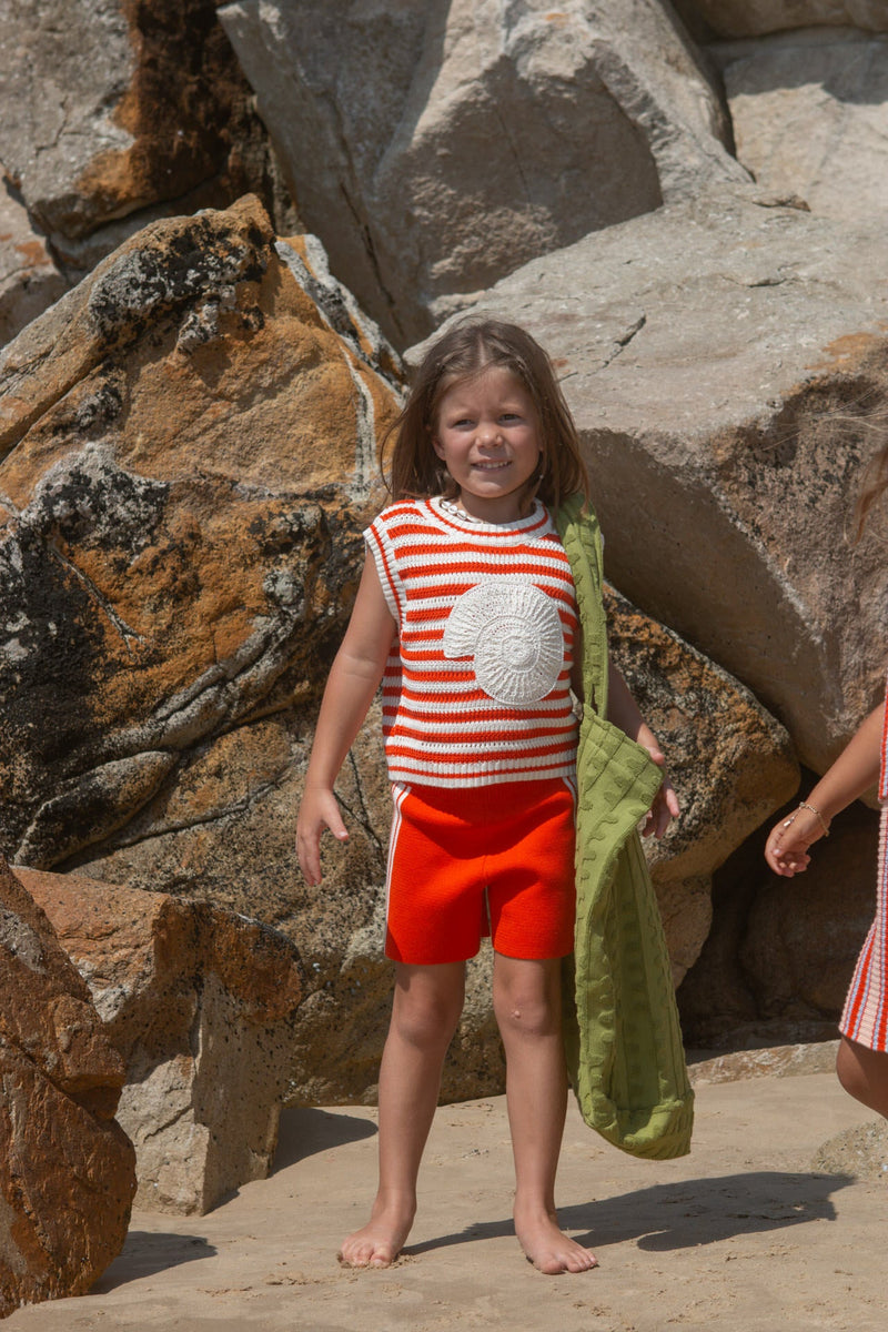 Young girl in a red and white striped vest with a crochet shell.