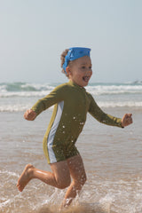 Child running on a beach wearing a green swimsuit and blue snorkle.